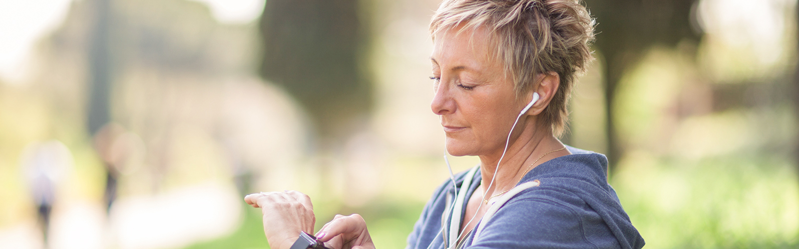 Une joggeuse avec des écouteurs dans les oreilles regarde l’heure sur sa montre Une joggeuse avec des écouteurs dans les oreilles regarde l’heure sur sa montre